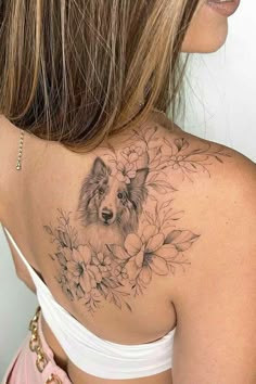 the back of a woman's shoulder with a dog and flowers tattoo on it