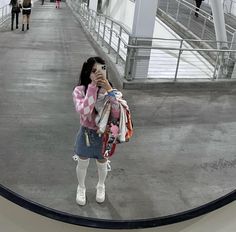 a woman taking a selfie with her cell phone in front of an escalator