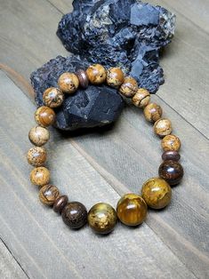 If warm earthy colors are your jam then this bracelet is for you. The backbone of this bracelet is 8mm Picture Jasper. The perfect Jasper that oozes earth energy. Up front there's three large 12mm Nellites flanked on each side by a 10mm Bronzite. Once again Nellite is the mineral vein where Pietersite and Tiger Eye collide. I apologize for repeating that description in this and other posts but it's just not a well known stone. The metal spacers are copper coated brass beads. They look like cute Earthy Brown Beaded Bracelets With Gemstone Beads, Earthy Brown Bracelets With Gemstone Beads, Earthy Brown Jasper Beaded Bracelets, Earthy Brown Gemstone Beads Bracelets, Brown Jasper Round Bead Bracelets, Brown Jasper Bracelets With Natural Stones, Brown Jasper Bracelets With Round Beads, Earth Energy, Jasper Bracelet