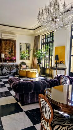 a living room filled with lots of furniture and a chandelier hanging from the ceiling