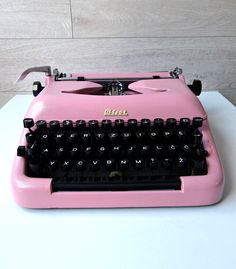 a pink typewriter sitting on top of a white table