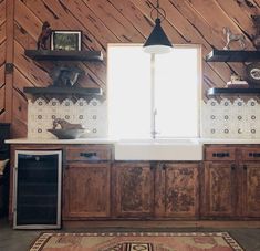 a kitchen with wood paneling and white counter tops on top of a rug next to a window