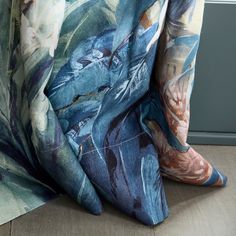 a blue and white floral print curtain hanging on the side of a wooden floor