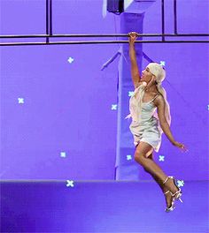 a female tennis player jumping up in the air with her racket to hit the ball