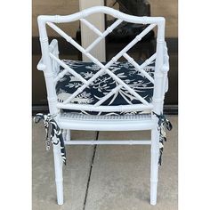 a white wicker chair with blue and white fabric on the armrests, sitting in front of a door