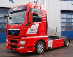 a red semi truck parked in front of a building