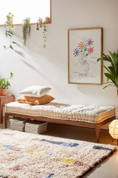 a bed sitting on top of a wooden floor next to a plant in a room