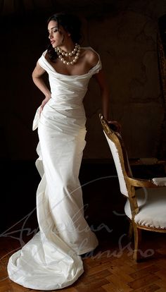 a woman in a white dress standing next to a chair