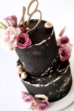 a black and white cake with pink flowers on top is featured in an instagram