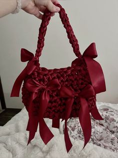 a woman holding a red purse on top of a white bed covered in lace and bows