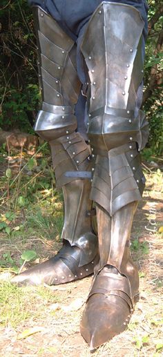 a man in armor standing on the ground with his legs spread out and one foot propped up