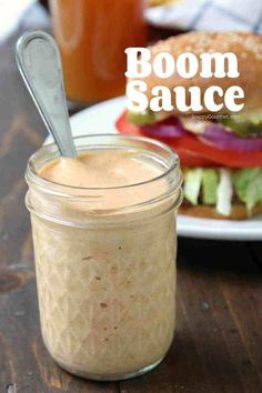 a jar filled with food sitting on top of a wooden table next to a sandwich