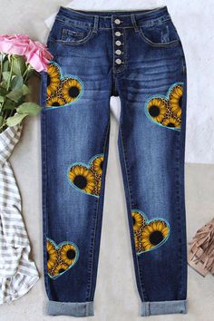 a pair of jeans with sunflowers on them and a pink rose next to it