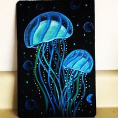 an acrylic painting of two jellyfish on a black board with blue bubbles