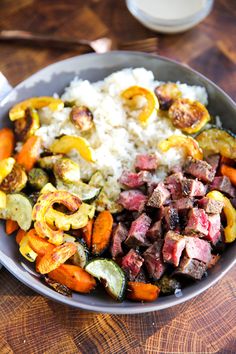 a bowl filled with meat and vegetables on top of a wooden table