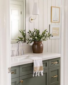 a bathroom sink sitting under a mirror next to a green cabinet and white counter top