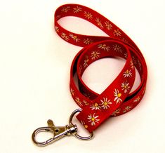 "Colourful daisy print on red background neck strap lanyard 15mm (non-detachable clasp, 15mm width) Bright white and yeloow flowers on a red background. High quality UK printed ID holder lanyards, printed on both sides, fitted with a metal clip, to be worn around the neck to carry ID, access cards, keys etc.   Product code : H-270 Hand made in the UK Size: 93cms  (36\") Width : 15mm  (0.78\") Silver metal clip *  Great quality and value *  Beautifully coloured, bright vivid sublimation print *  Lightweight *  Smooth polyester fabric remains comfortable to wear *  Long lasting metal trigger clip UK manufacturer and seller All prices include free UK post & packing All lanyards are individually packed Available in 3 options: Standard lanyard with just a metal hook Safety breakaway lanyard wit Red Lanyards With Key Leash, Adjustable Red Lanyard With Key Leash, Adjustable Red Lanyard As Gift, Red Lanyard With Key Leash As Gift, Red Lanyards With Key Leash For Gifts, Personalized Lanyards, Background High Quality, Custom Lanyards, Key Lanyard