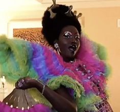 a woman dressed in colorful clothing holding a fan