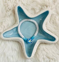 a blue and white starfish shaped dish with a beaded bracelet on it's side