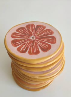 a stack of pink and yellow coasters on top of each other with orange slices painted on them