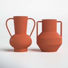 two orange vases sitting next to each other on a white surface with no one around them