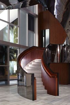 an elegant staircase with glass railings and wood paneling in a modern home setting