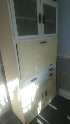 an old yellow cabinet with glass doors and drawers