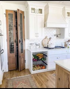 a kitchen with white cabinets and wooden floors, an area rug is on the floor