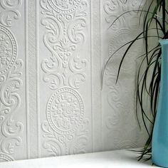 a blue vase sitting on top of a white shelf next to a potted plant