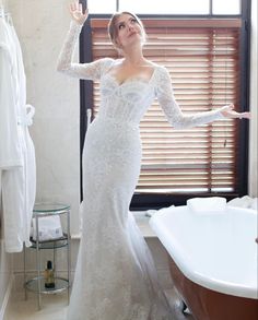 a woman in a wedding dress standing next to a bath tub