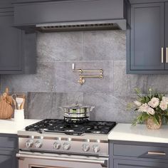 a stove top oven sitting inside of a kitchen next to gray cabinets and counter tops