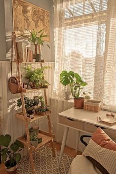 a living room filled with lots of plants next to a white desk and window sill