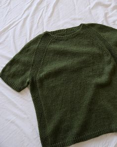 a green sweater laying on top of a bed