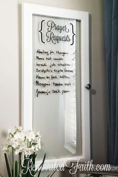 a white framed mirror sitting on top of a table next to a vase filled with flowers