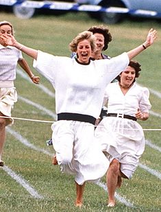 three women running across a field with their arms in the air and one woman holding her hands out