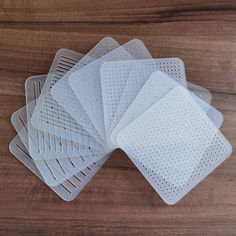 five plastic coasters with holes on them sitting on a wooden table next to each other