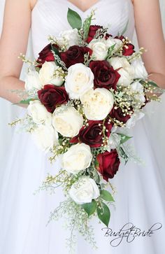 a bride holding a bouquet of white and red flowers