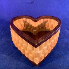 a heart shaped wooden box sitting on top of a blue surface