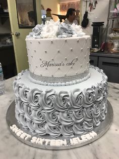 a three tiered cake with white frosting and silver decorations on the bottom layer