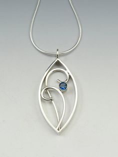 Sterling silver hand fabricated filigree pendant measures 1.5" high and 3/4" wide, offset with a faceted 5mm London Blue Topaz gemstone accent and hung from a 1mm snake chain.  Simple and elegantI can use other gemstones upon request, or a birthstone, message me for pricing.Created from responsibly sourced materials where possible. Each piece is handmade, because of this there may be slight variations in your finished piece from the photo shown. Please allow 1-2 weeks for fabrication and deliver