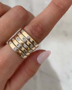 a woman's hand holding a gold ring with diamonds on it and two fingers