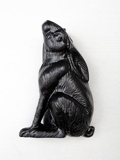 a black ceramic animal sitting on its hind legs and looking up at the sky, against a white background