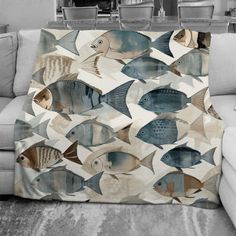 a living room area with a couch, chair and rug covered in an ocean themed throw blanket