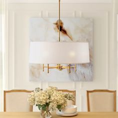 a chandelier hangs over a dining room table with white flowers in vases