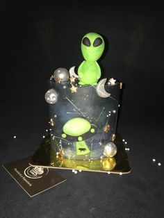 an alien birthday cake with stars and planets on it's side, sitting next to a card