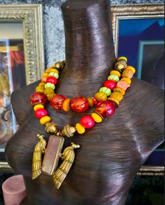 An exotic red, yellow and orange African Statement Necklace is a funky ethnic melange that will enhance your face, beautifully!! This mixed media piece features Tibetan Resin, Brass Chinese Coins, ornate Vintage Brass Beads, Yellow Resin, red magnesite, coral, Picasso Jasper, Nepalese glass, Wood barrels, wavy copper metal spacers, Moroccan Resin, and frosted agates. The 3.5" x 3" Tibetan Brass Repousse Double Peacock Pendant with Inlaid Jasper integrates all the bold and chunky materials and grounds the piece in luxury. Striking worn with a tan or on women if color, year-round. Adjusts from 18-21" with gold tone hardware and a fine hook clasp. Note the funky beaded dangle suspended from the 3" extender chain which will sashay down your back. A high end, dramatic piece from the Atelier of Traditional One-of-a-kind Multicolor Beaded Necklace, Multicolor Large Beads Necklace For Rituals, Festive Multicolor Artisan Necklaces, Multicolor Necklaces With Large Beads For Rituals, Artisan Orange Beaded Necklaces For Festivals, Multicolor Beaded Necklaces For Rituals, Unique Multicolor Decorative Necklaces, Bohemian Orange Necklaces For Festive Occasions, Bohemian Orange Necklace For Festive Occasions