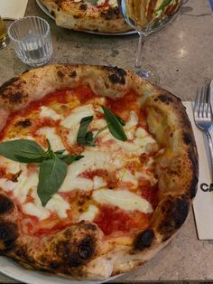 a pizza sitting on top of a white plate next to a fork and glassware