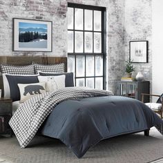 a bedroom with brick walls and grey bedding