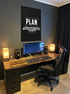 a desk with a monitor, keyboard and speakers in front of a painting on the wall