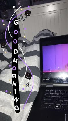 a laptop computer sitting on top of a bed next to a purple and black pillow